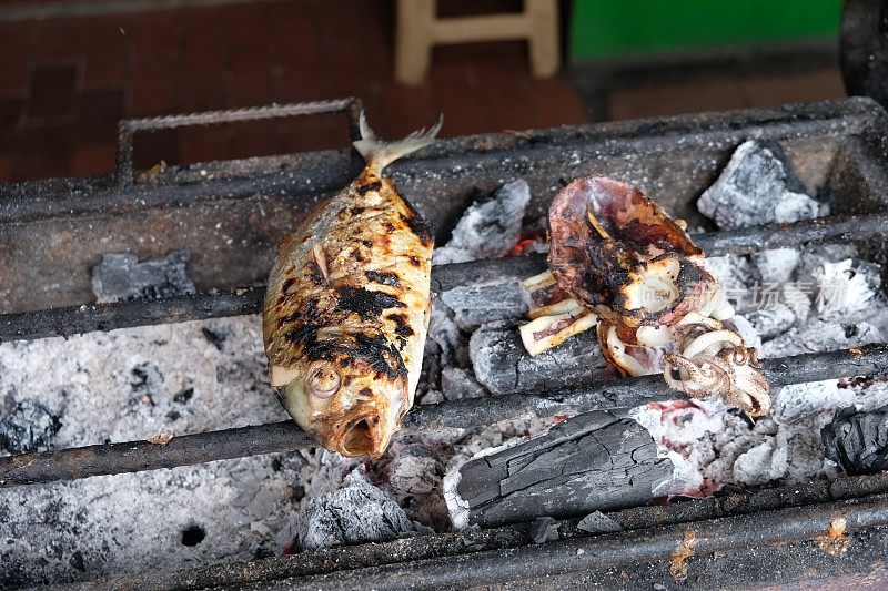 用木炭烤架烤的石斑鱼。烤海鱼。印尼的食物。Ikan kerapu bakar。鱿鱼烤。cumi bakar。